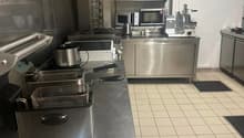 commercial kitchen with oven, microwave, deep fryers, and counter tops, tile flooring