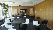 modern office room with round tables, chairs, wooden walls, large windows, whiteboard, TV