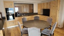 Modern kitchen with wooden cabinets, a round dining table, wooden floor, a sink with faucet, oven and refrigerator