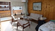 wooden walls, white rug, couch, chair, table with books, balcony, window with view