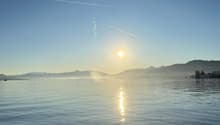 Wide view of a lake at sunset with ducks swimming in the foreground