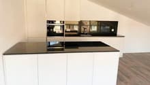 white kitchen, black countertops, integrated appliances, wooden flooring