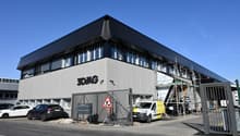 Office building, 3D/AG sign, multiple cars parked, two gates, construction scaffolding