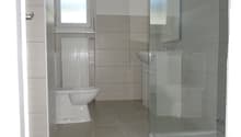Bathroom with tile flooring, shower, sink, toilet, and a heater.