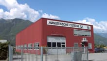 Red industrial building with large garage doors, multiple windows, and a sign reading 'MANUTENZIONE CISTERNE SA'.