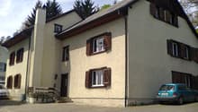 2 story house, beige walls, brown shutters, car parked in front, brick driveway