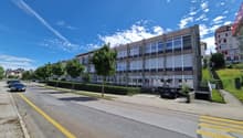 Multistory building, modern architecture, concrete exterior, numerous windows, parking area, streetlight, multiple parked cars