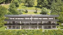 Modern building with glass balconies, raised ground floor, and a view of the mountain.