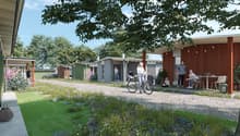 Modern homes with green exterior, garden with flowers, paved pathway, people with bicycles and chairs
