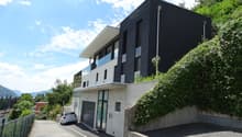Modern house, black and white exterior, large windows, garage, concrete wall, greenery