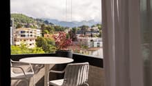 balcony, outdoor table and chairs, potted plant, city and mountain view