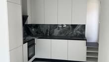 modern kitchen with white cabinets, black marble countertop, white tiled floor, built-in oven, sink, and shelves