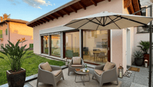 Outdoor seating area with 4 chairs, table, umbrella, rug, plants, and lanterns