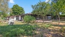 Villa dans un environnement verdoyant / a large rock in front of a home with trees