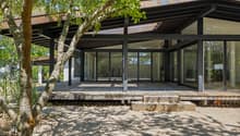 Villa avec baies vitrées offrant une vue paisible / a modern home with a large deck on a sunny day