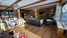 living room with wooden floor, wooden beams, dining table, couch, TV, fireplace, dining chairs, wooden cabinet, lamps, picture frames
