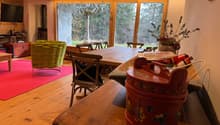 Wooden floor, dining table, chairs, TV, large glass doors, red carpet, decorative items, flowers