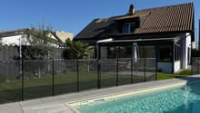 Modern house with brown roof, glass windows, black fence, swimming pool, wooden deck