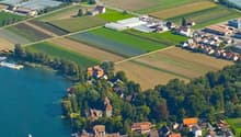 Aerial view of several buildings, houses and farmlands by a river