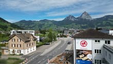 House with brown exterior and windows, parking lot, mountains in the background