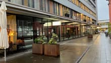 modern office building with glass walls, metal roof, patio with table and chairs, outdoor plants