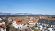 white building with red roof, balcony, solar panels on roof, mountains in the distance