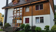 Detached house, wood and white brick, tiled roof, multiple windows, front stairs, landscaped front