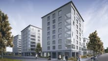 Modern apartment building with multiple floors, glass windows, balconies, and a flat roof.