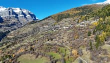 Mountain village, winding roads, mountainous landscape, green fields, snowy peaks, dense trees