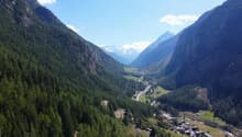 Dense coniferous forest, river, mountains, villages, clear blue sky