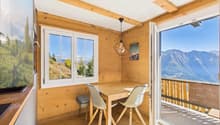 Wooden table, 2 chairs, windows, balcony, wooden floor, open door, lamp