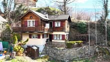 2 story wooden house, red shutters, balcony, stone wall, stairs, chimney