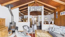 wooden ceiling, fireplace, wooden floor, gray couch, wooden coffee table, wooden chairs, wooden cabinet, basket, radiator