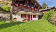 2 story chalet, wooden balcony, red shutters, white walls, wooden bench, wooden storage box, well-maintained lawn