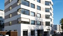 white and brown building with several windows, multiple floors