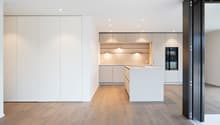an open kitchen, central island, built-in cabinets, wooden floor, white walls, modern fixtures, an oven