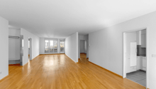 empty room with hardwood floors, large windows, balcony