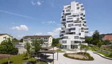 White multistory residential building with balconies and raised ground floor