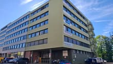 Office building, 3 floors, multiple windows, parking lot, motorcycles and cars parked