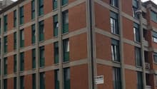 Commercial building, 5 stories, brick wall, green window frames, white air conditioners, awnings, storefronts, street level, 18 units