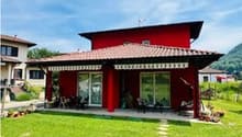 Red house, terrace, garden, patio, green grass, mountain in background