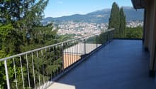 balcony with wood flooring, metal railings, view of a city with mountains in the background