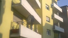 Yellow apartment building, multiple balconies, canopy awning, satellite dish