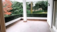 empty balcony with tiled floor and column, plants, trees in the garden