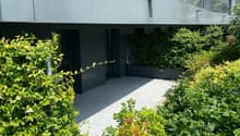 Modern apartment building, metallic facade, glass windows, greenery in the front