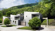 Modern concrete residential building, multiple levels, large windows, garage