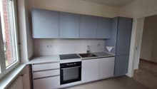 Modern kitchen with white cabinets, gray countertops, a sink, and a gas stove. The kitchen is equipped with a built-in oven and a towel hanging on the wall.