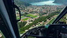 Aerial view of a city with mountains, a lake, and a green field