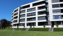 Modern apartment building, white exterior, large windows, balconies, landscaped lawn