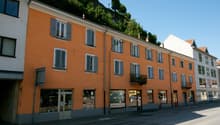 Orange facade, 4 floors, multiple balconies, windows, shops on ground floor